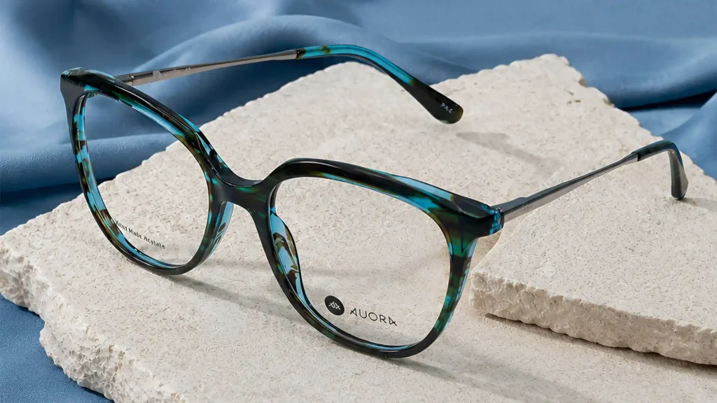 Auora Eyewear blue tortoiseshell optical frame on a textured stone surface.