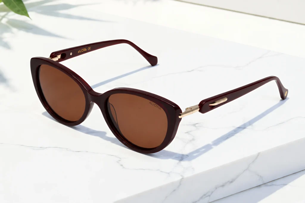 Auora Eyewear round burgundy sunglasses on a white marble surface.